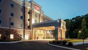 A Hampton Inn hotel with a stone facade, a clear entrance, and a parking area.