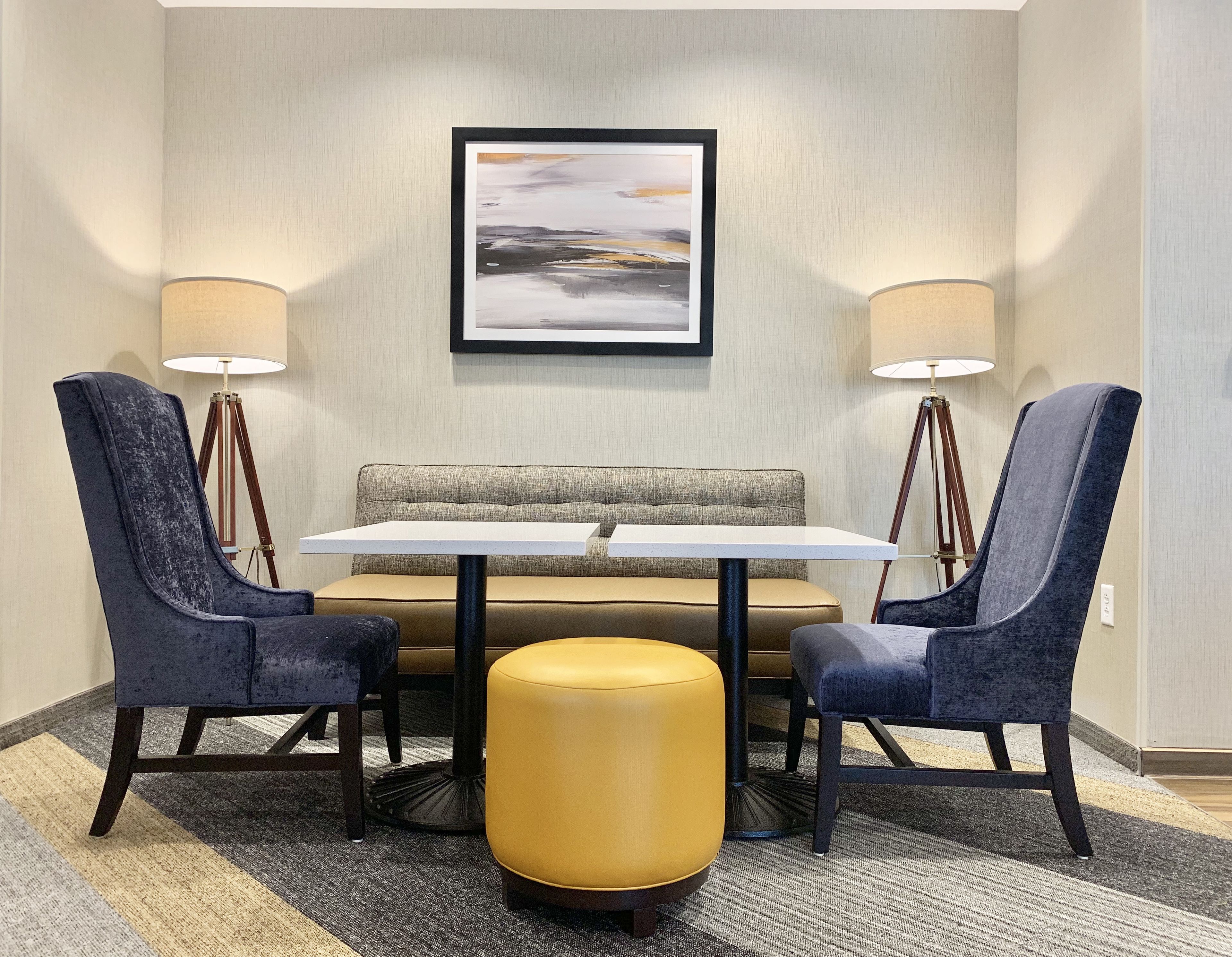A seating area with a round table, two chairs, a sofa, and two floor lamps.