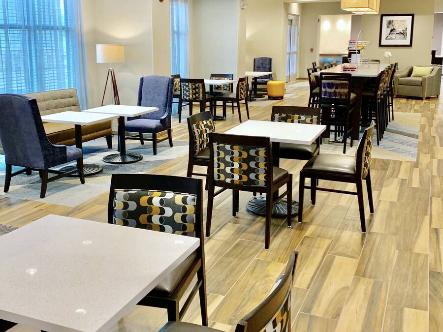 Een hotel lobby met verschillende zithoeken, waaronder tafels en stoelen, een bank en een klein eetgedeelte.
