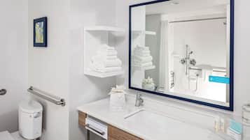 Une salle de bain moderne avec un lavabo blanc, un grand miroir et un porte-serviettes.