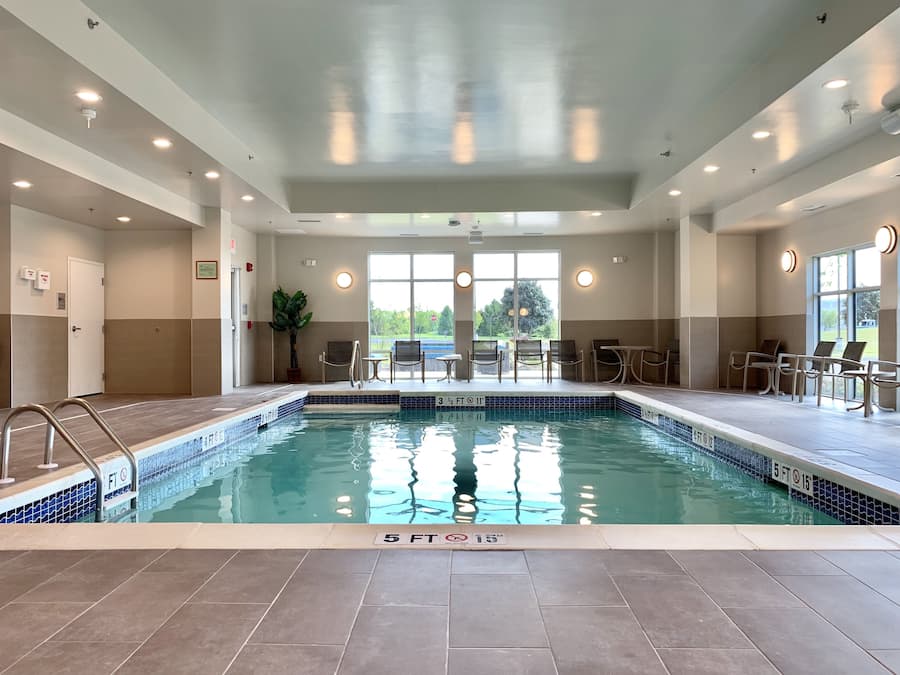Une piscine à l’eau claire, entourée d’un sol carrelé et dotée d’un plafond avec des spots encastrés.