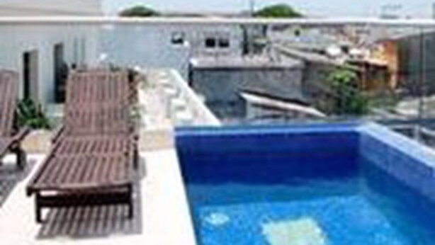 A rooftop pool area with lounge chairs and a clear view of the city skyline. - Apartamentos en el Centro Histórico (Cartagena)