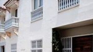 A two-story building with a balcony on the second floor, a garage door, and a small potted plant. - Apartamentos en el Centro Histórico (Cartagena)