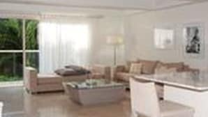 A modern living room with a sofa, coffee table, and a dining area with chairs. - Apartamentos en el Centro Histórico (Cartagena)