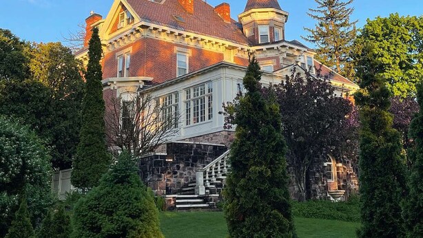 A large, historic building with a prominent tower, surrounded by well-maintained gardens and tall trees. - Blind Tiger Burlington (Burlington)
