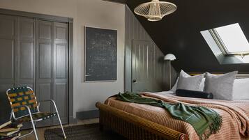 A bedroom with a bed, a chair, a large window, and a ceiling light.