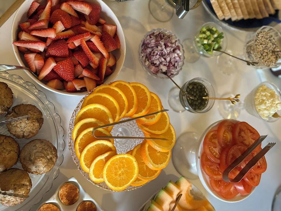 A table with various food items including strawberries, blueberries, oranges, and melon slices.