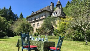 A table set outdoors with two chairs, a stone building in the background, and a clear sky.