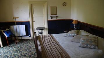 A bedroom with a bed, bedside table, lamp, chair, and a small table with a mirror.
