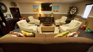 A living room with a brown sofa, beige armchairs, a coffee table, and a flat-screen TV mounted on the wall. - Ocean Key Resort spacious 1 bedroom suite (Virginia Beach)