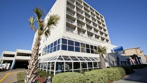 A modern hotel with a glass facade, multiple balconies, and a sign for Ocean Key Resort. - Ocean Key Resort spacious 1 bedroom suite (Virginia Beach)