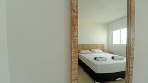 Ein Hotelzimmer mit einem großen Spiegel, einem Bett mit weißer Bettwäsche und einem Holzkopfende.
