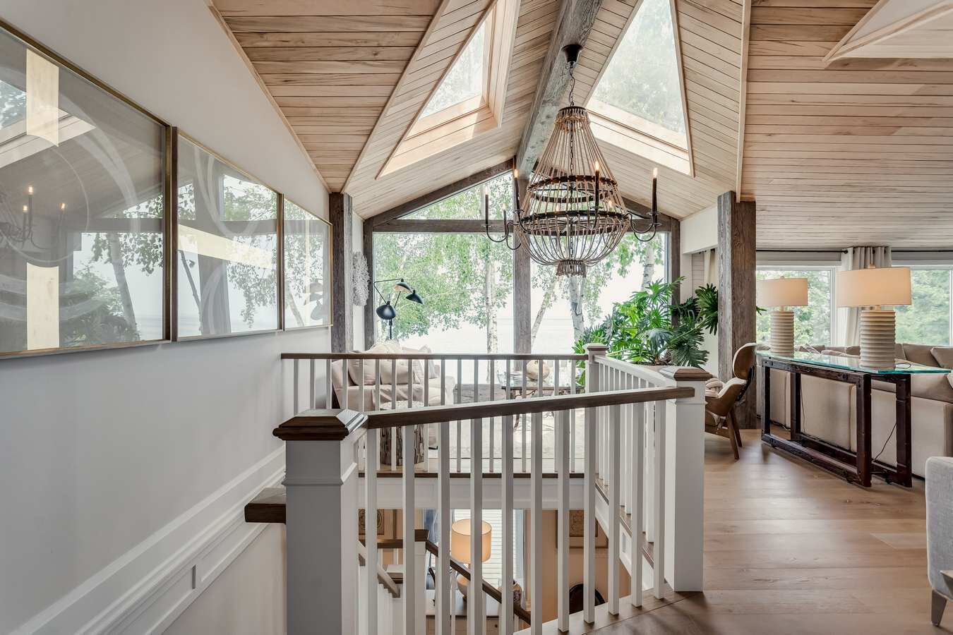 Un ambiente spazioso con soffitto in legno, ampie finestre e una scala che conduce a un piano superiore.