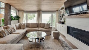 Una sala de estar con un sofá modular, una mesa de centro de vidrio y una chimenea.