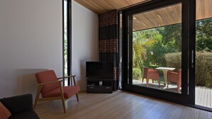 A modern living room with a TV, a sofa, and a dining area with chairs.