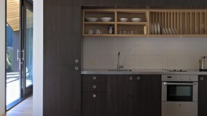 A modern kitchen with dark wood cabinets, a stainless steel oven, and a built-in shelf with dishes.