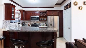 Una cocina con gabinetes de madera oscura, encimera de granito, electrodomésticos de acero inoxidable y una puerta blanca.