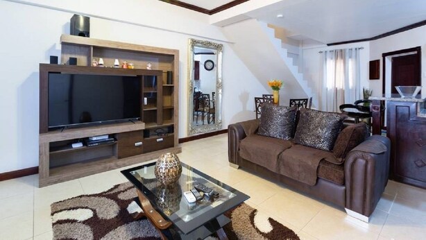Una sala de estar moderna con una televisión de pantalla plana, un sofá, una mesa de centro y una escalera.