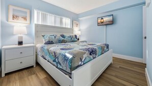 A bedroom with a bed, nightstands, a lamp, and wall art.