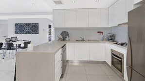 Una cocina moderna con armarios blancos, una isla central y un horno empotrado.