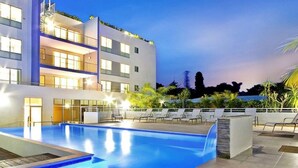 Un hotel moderno con piscina, zona de estar al aire libre y fachada bien iluminada.