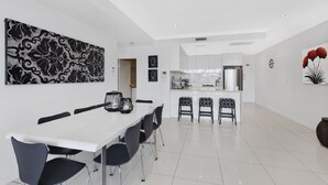 Una cocina moderna con armarios blancos, una isla central y taburetes de bar.