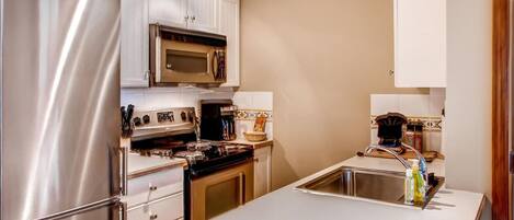 A modern kitchen with stainless steel appliances, white cabinetry, and a central island with a sink.