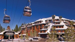 Un lodge de varios pisos con teleféricos, fachada de madera y paisajes nevados.