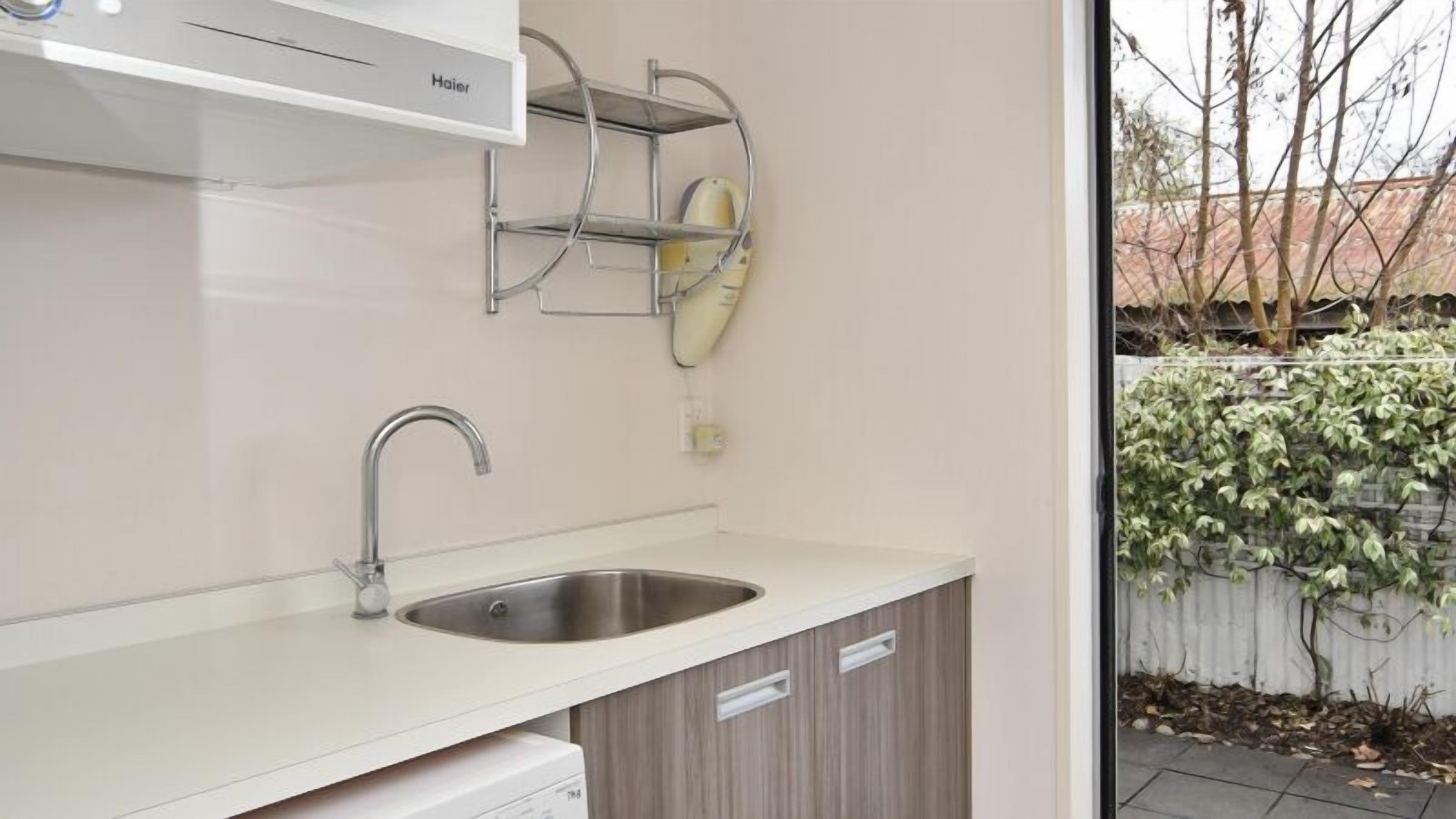A modern kitchen with a stainless steel sink, a white countertop, and a built-in oven.