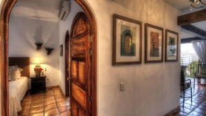 Un couloir avec une porte en bois, un lit avec une table de chevet et des tableaux encadrés accrochés au mur.
