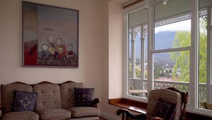 A living room with a sofa, armchairs, and a coffee table. There is a large window with a view of a landscape.