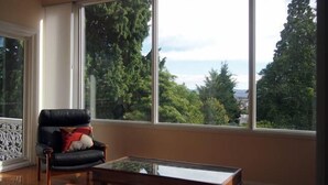 A room with a large window, a leather chair, and a wooden coffee table.