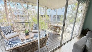 Un patio techado al aire libre con mobiliario de mimbre, una mesa redonda y un sofá.