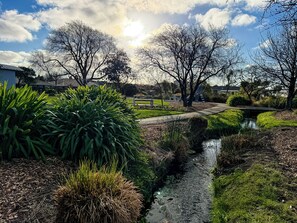 A tranquil outdoor setting with a narrow water channel, lush greenery, and trees.