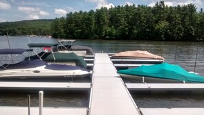 A dock with several boats, a clear sky, and a forested hill in the background. - Lakefront Log Home w/ Dock Slip, 30% Weekly Discount, 2 Miles from Nat. Park (Swanton)