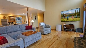 A living room with a sofa, a chair, a television, and a stone fireplace. - 24 Rogue-Sunriver, Oregon: Hot Tub, BBQ, WiFi, SHARC Aquatics, Tubing Hill, Mt. Bachelor, Golf, Deschutes River, Tennis, Bike Paths (Sunriver)