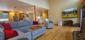 A living room with a sofa, a chair, a television, and a stone fireplace.