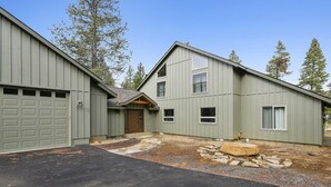 A two-story building with a garage, a stone pathway, and a small wooden deck. - 24 Rogue-Sunriver, Oregon: Hot Tub, BBQ, WiFi, SHARC Aquatics, Tubing Hill, Mt. Bachelor, Golf, Deschutes River, Tennis, Bike Paths (Sunriver)