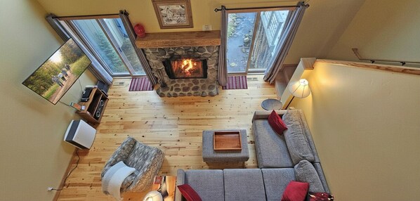 A cozy living room with a stone fireplace, a sofa, a television, and a fireplace screen.