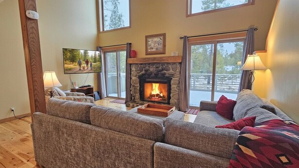 A cozy living room with a fireplace, comfortable seating, and large windows. - 24 Rogue-Sunriver, Oregon: Hot Tub, BBQ, WiFi, SHARC Aquatics, Tubing Hill, Mt. Bachelor, Golf, Deschutes River, Tennis, Bike Paths (Sunriver)
