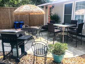 An outdoor patio area with a grill, seating, and a potted plant. - Cute Bungalow, Hot tub, game room,fenced yard (Sneads Ferry)