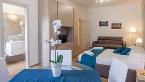 A modern hotel room with a glass table, a potted orchid, a sofa, two beds, a TV, and artwork on the wall. - THE MUSE your home facing St. Peter’s Dome  (Roma)