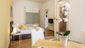 A hotel room with a bed, bedside table, and a dining area with a table and chairs. - THE MUSE your home facing St. Peter’s Dome  (Roma)