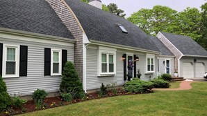 A row of two-story houses with grey siding and black shutters, a well-maintained lawn, and a driveway leading to a garage. - Fun & Sun in Osterville MA - Sleeps 10, Beach Pass (Barnstable)