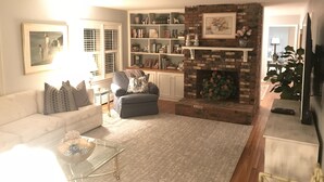 A living room with a fireplace, a sofa, a coffee table, and a bookshelf. - Fun & Sun in Osterville MA - Sleeps 10, Beach Pass (Barnstable)