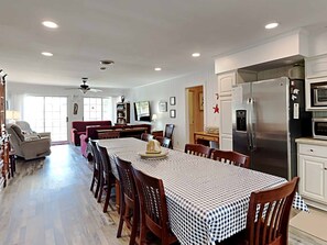 A spacious dining area with a large table, chairs, and a kitchen with modern appliances.