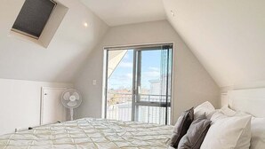 Un dormitorio con una cama grande, un ventilador de techo y una ventana con vistas.
