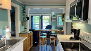 Una cocina con una isla central, taburetes de bar, cafetera y microondas.