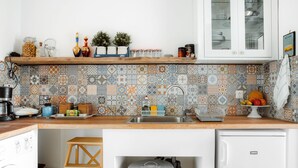 Eine Küche mit gefliestem Rückspritzschutz, einer Holz Arbeitsplatte, einem Spülbecken und einem weißen Kühlschrank.