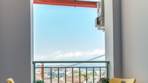 Ein Balkon mit zwei gelben Stühlen, einem kleinen Tisch und einem Blumentopf.